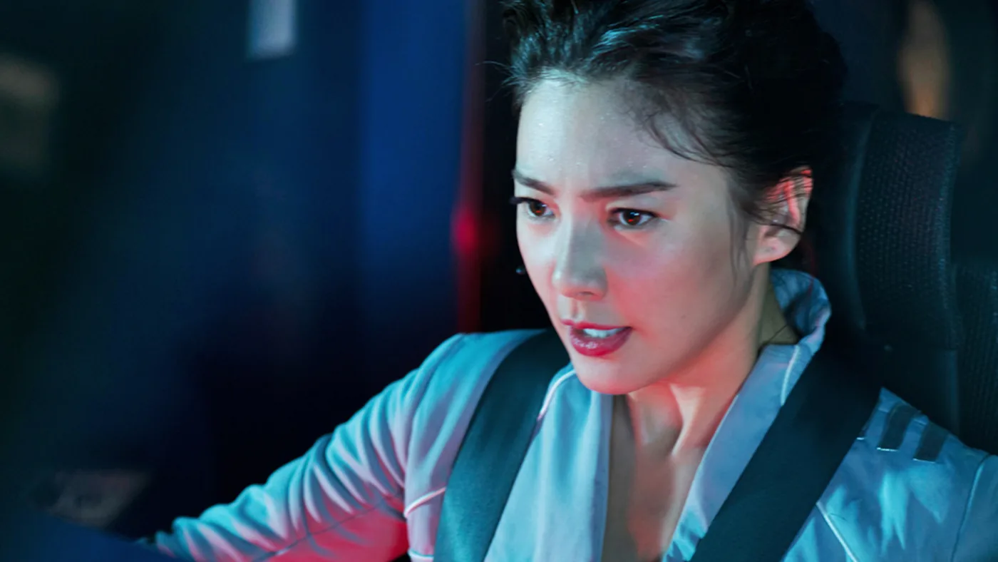Lian Ziyi at a broadcast console, lit by screens